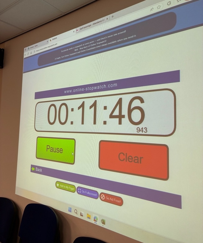 Times counting down from 15 minutes displayed on a projector in a classroom.